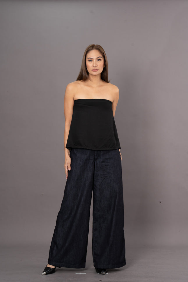 Woman wearing a black strapless tube top and wide-leg denim trousers pants