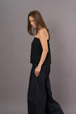 Woman wearing a black strapless tube top and wide-leg denim trousers pants