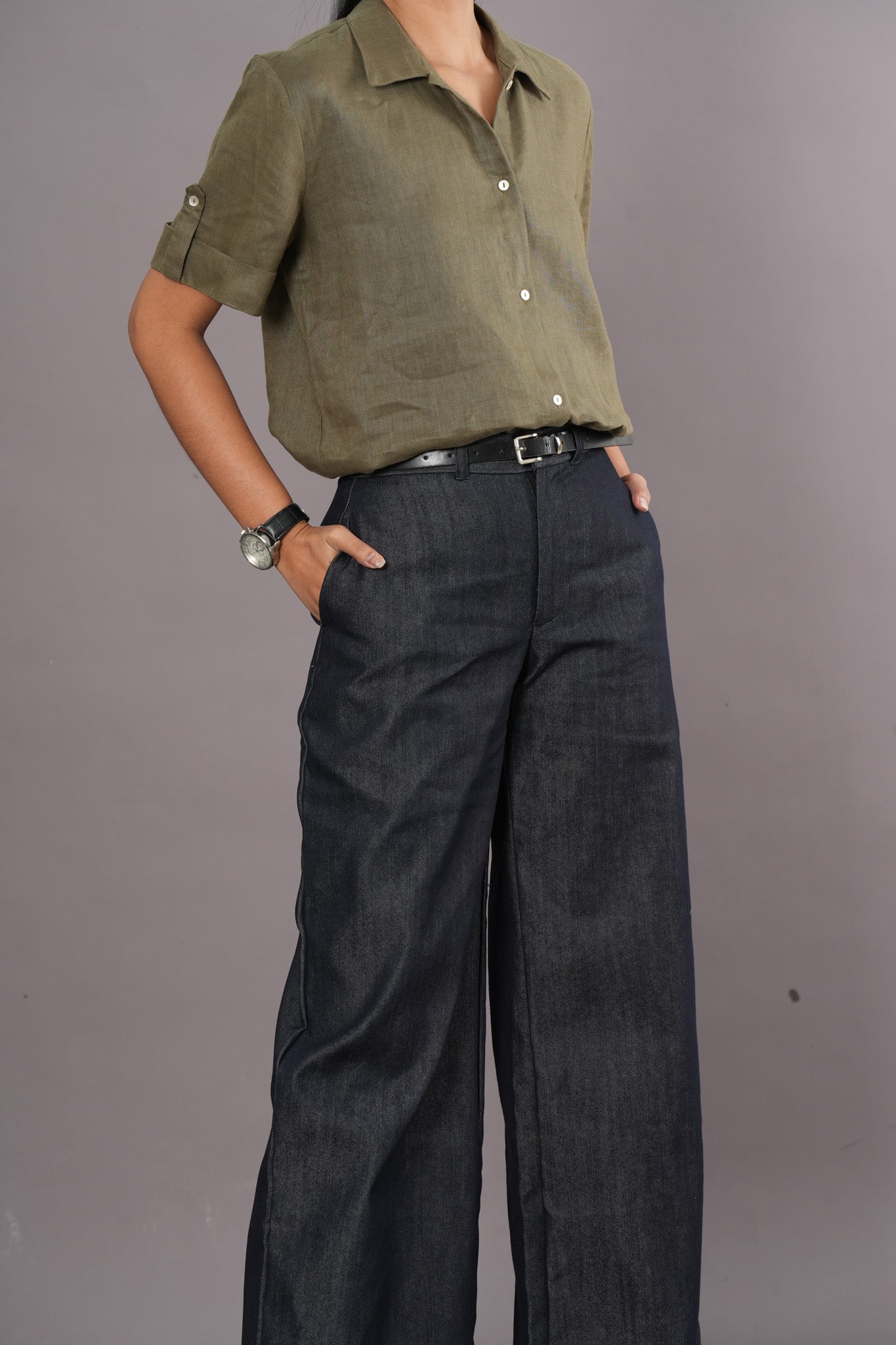 Woman wearing an olive green short sleeve polo and denim wide leg trousers